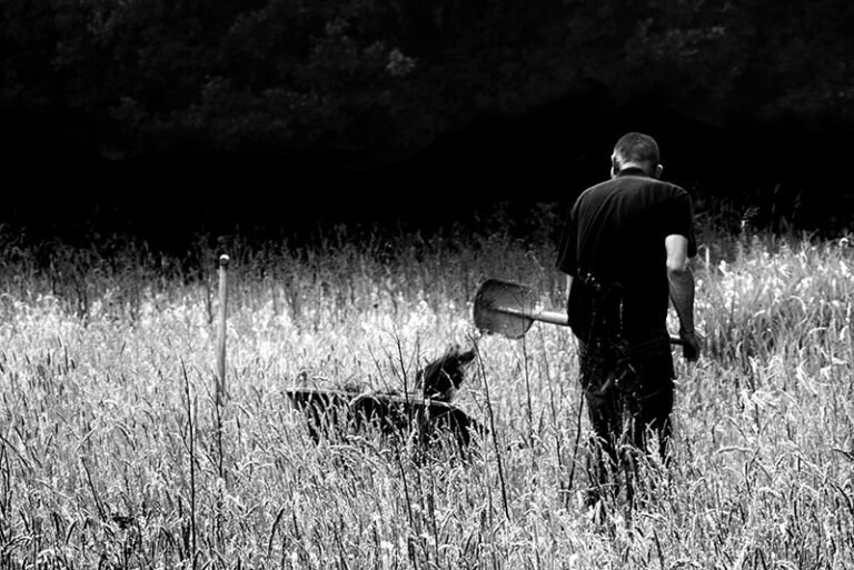 A man in a field with a shovel wonders, "Can I pan for gold in my backyard?