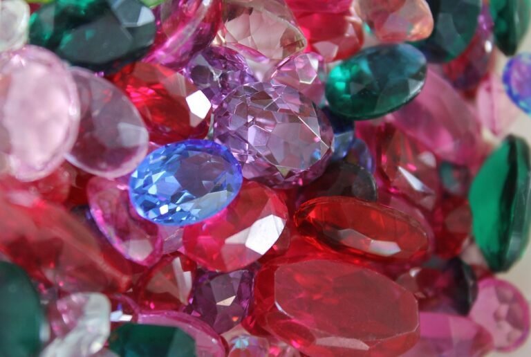 A close-up view of various colorful cut gemstones, including red, green, pink, blue, and purple stones, piled together—perfect for inspiring new Gemstone Discoveries.
