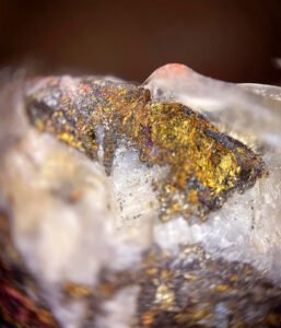 Close-up of a mineral sample with gold and brown metallic flecks embedded in a white, translucent crystalline matrix—ideal for identifying lode gold deposits.