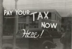 A black and white photo of a sign that says pay your tax now here, addressing the question 
