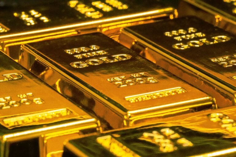Close-up view of several shiny gold bars stacked together, each labeled with weight and purity markings—an impressive display highlighting the geological origins of precious metals.