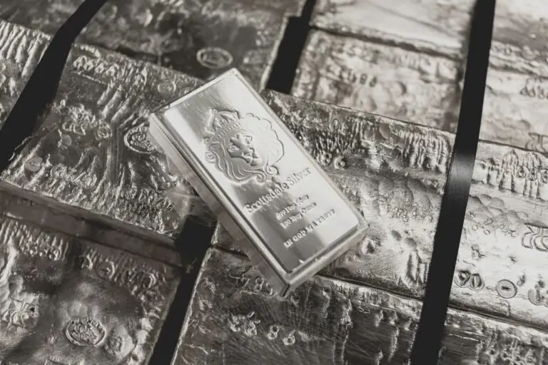 A stack of silver bars, featuring a prominently marked "Scottsdale Silver" piece with a lion emblem, rests atop others—a striking display in any Valuable Metals Overview.